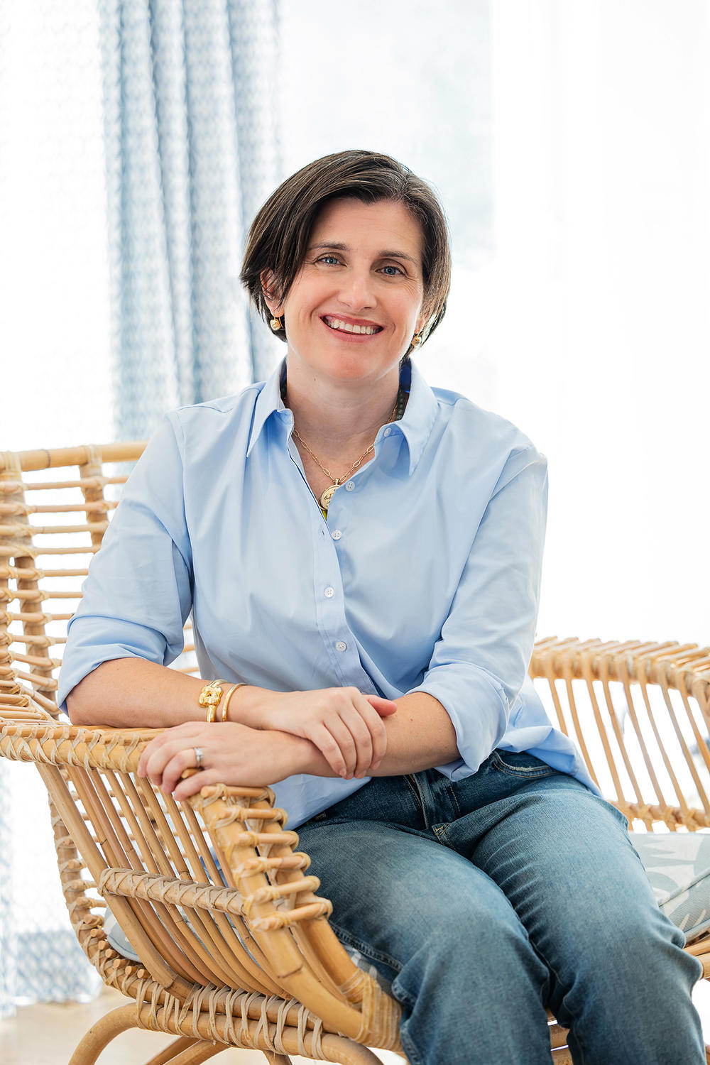 Katie Speetzen smiling, seated in a wicker chair