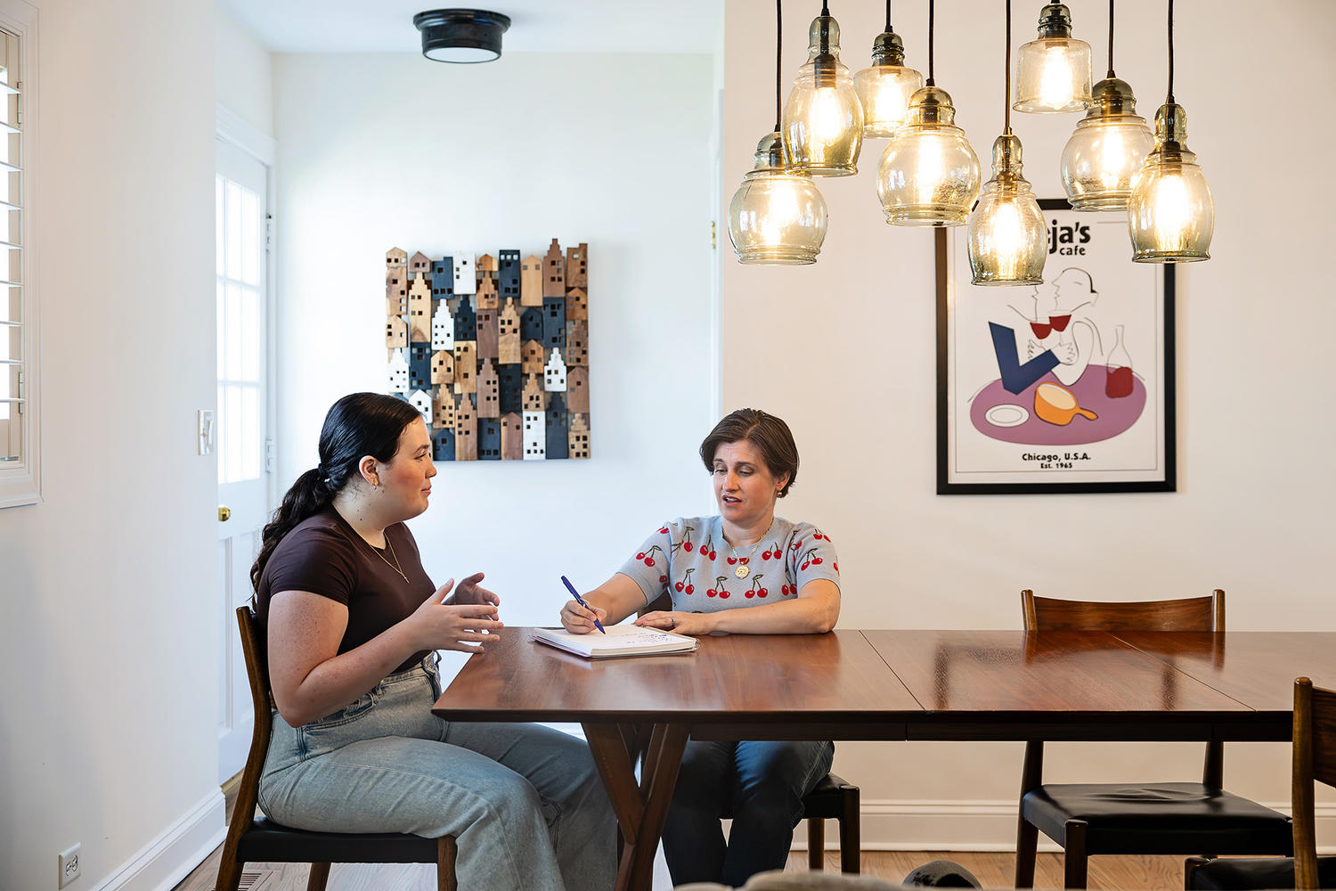 Katie and a student talking together at a dining table