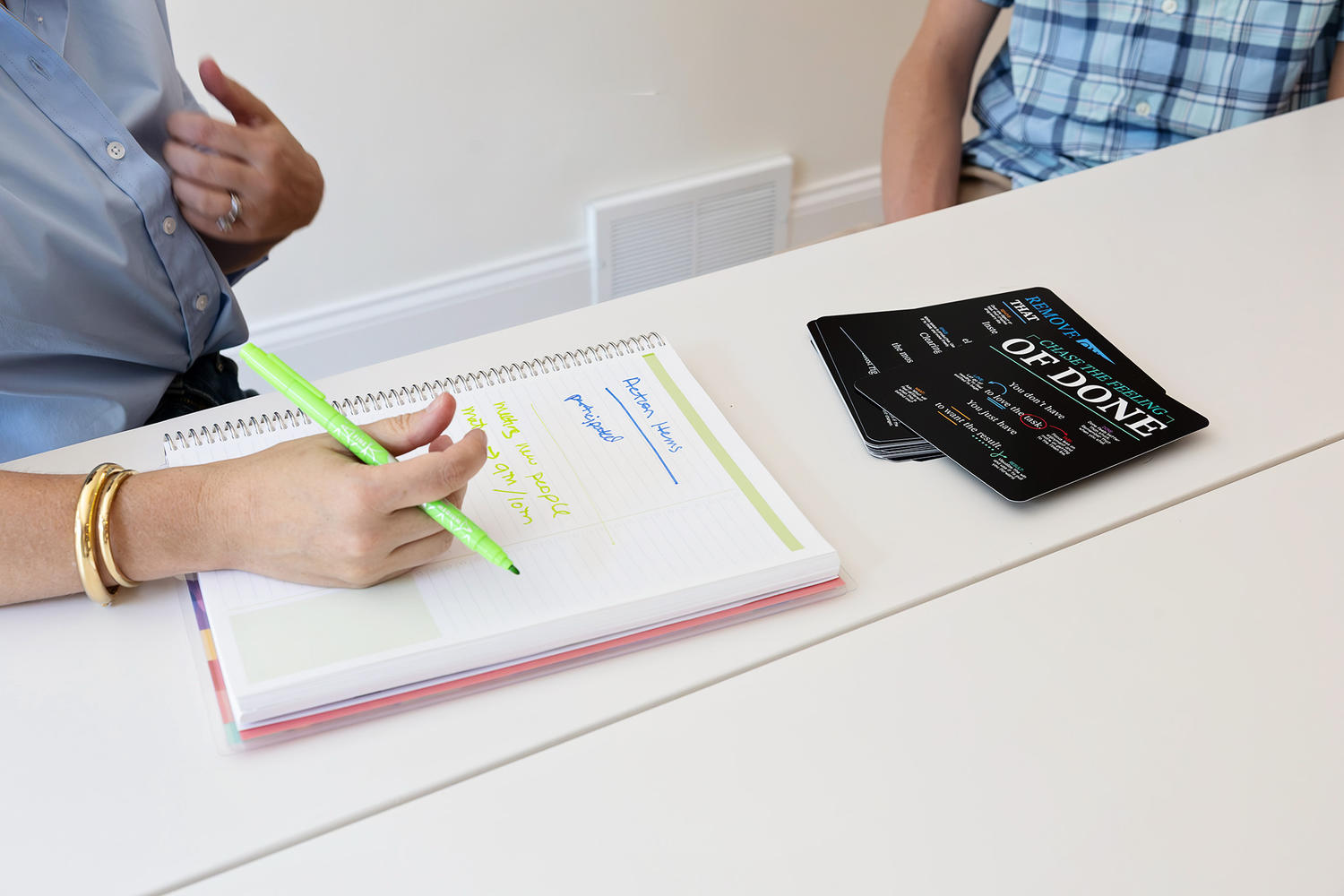 Hands writing action items in a planner during a coaching session