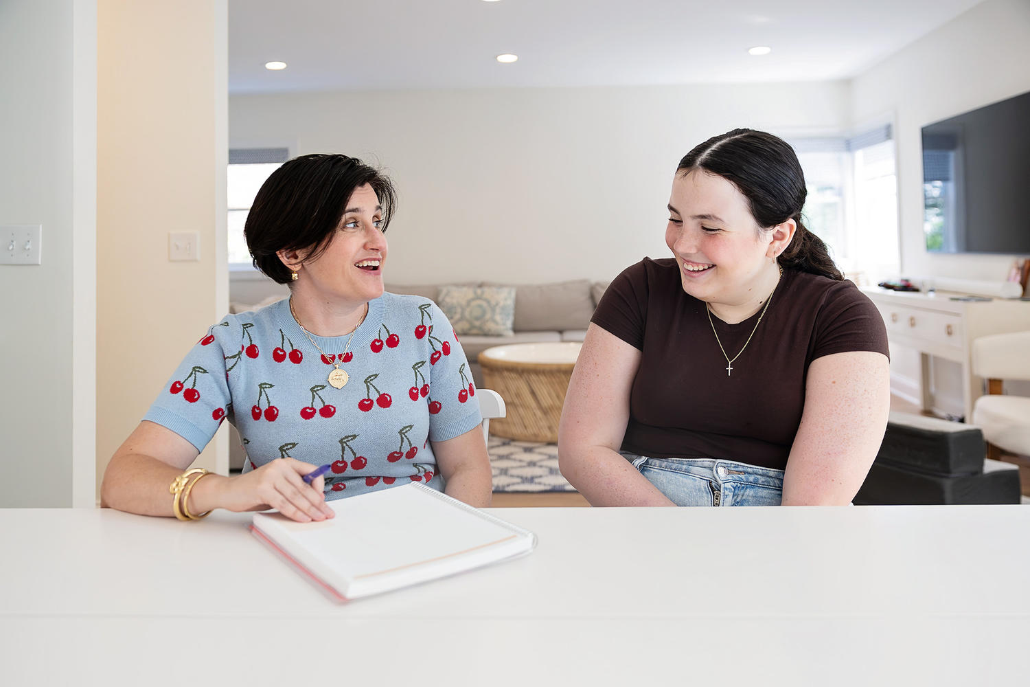 Katie and a student laughing together while reviewing a notebook